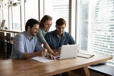 Three colleagues working together on a laptop and discussing content