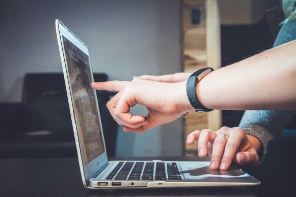 Hands pointing at something on a laptop to explain something