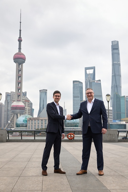 Two men are shaking hands. The Shanghai Tower can be seen in the background.